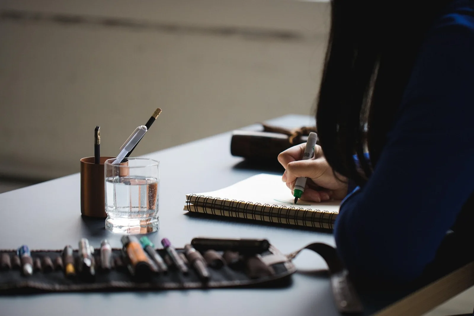 Woman closing her notebook at her desk in the evening, the first step in how to wind down before bed