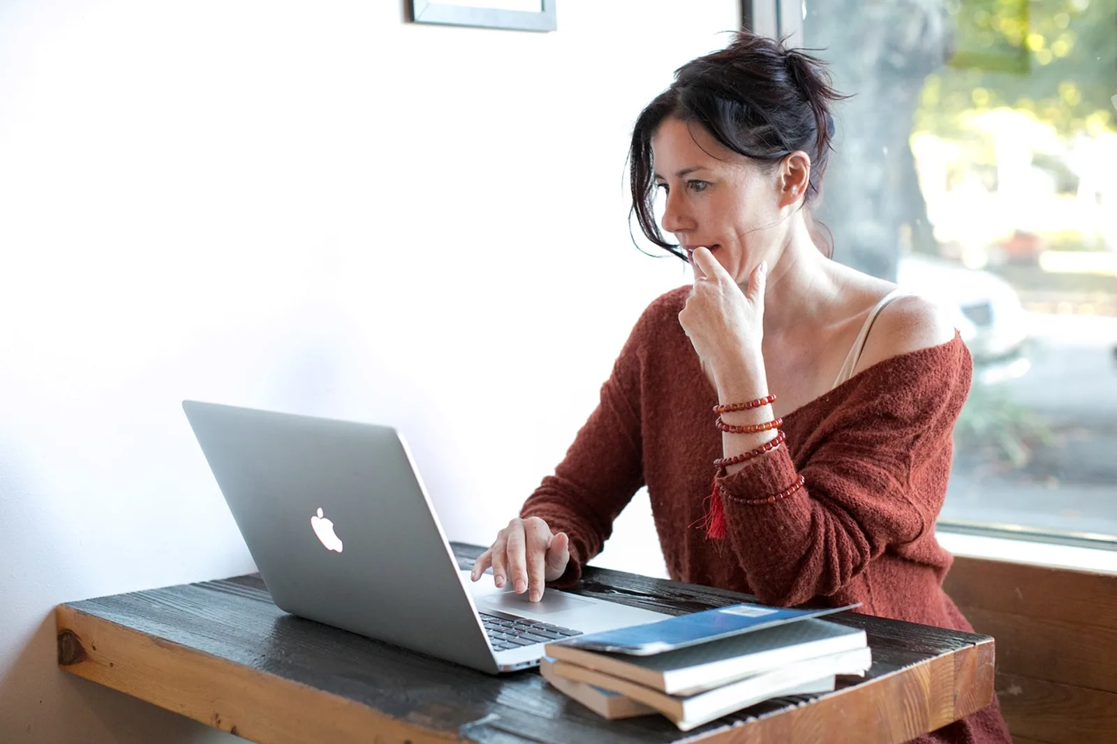 Woman at a desk in morning light hesitating before the first step, a moment that shows how to stop procrastinating
