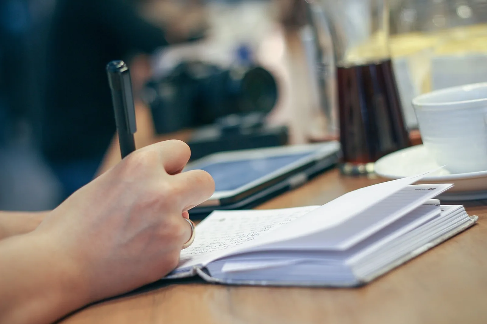 Hand writing notes in a notebook on a wooden table: a small routine for getting noticed at work