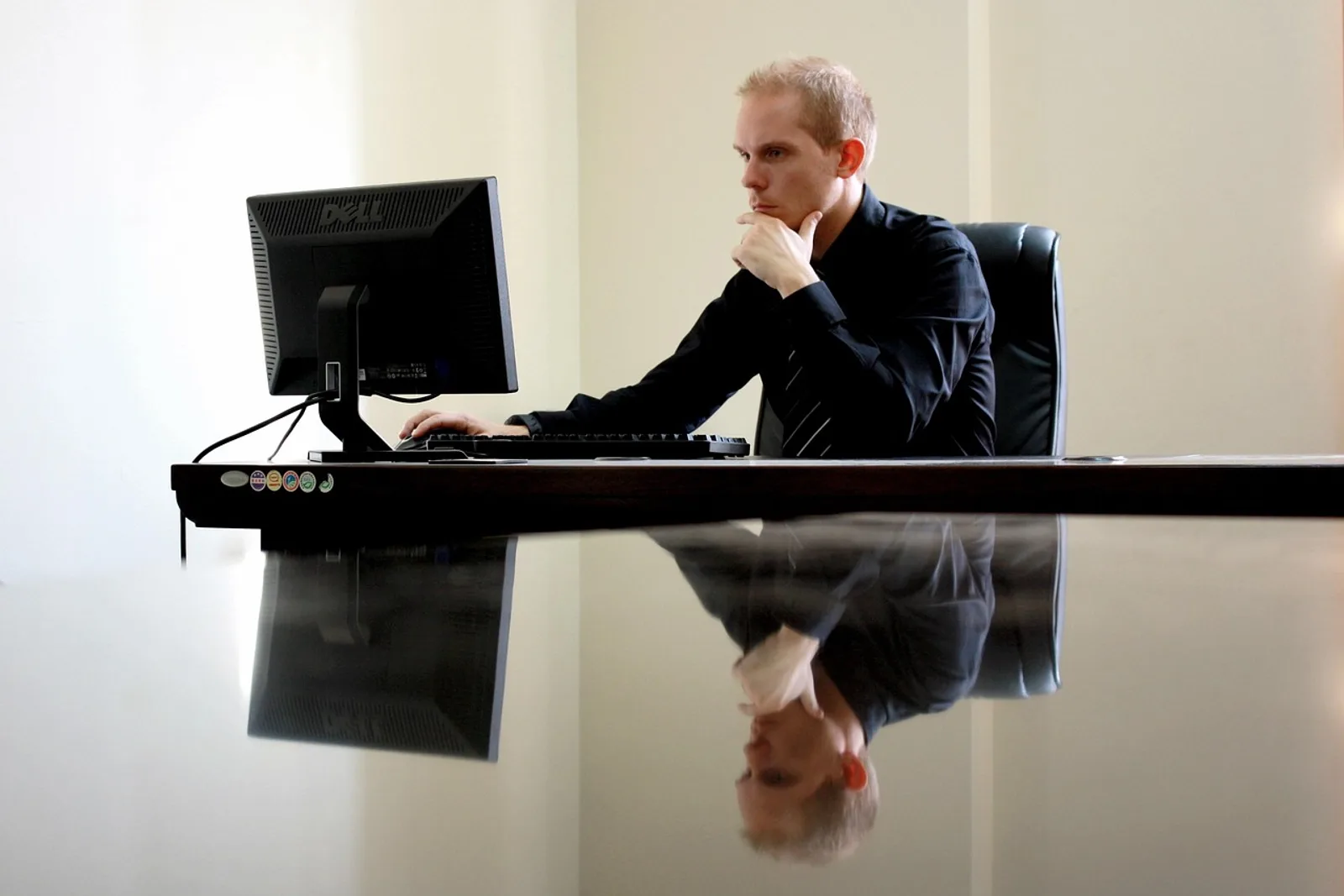 Entrepreneur thinking with his hand on his chin in front of a monitor, a typical moment for hypnosis for entrepreneurs at the office