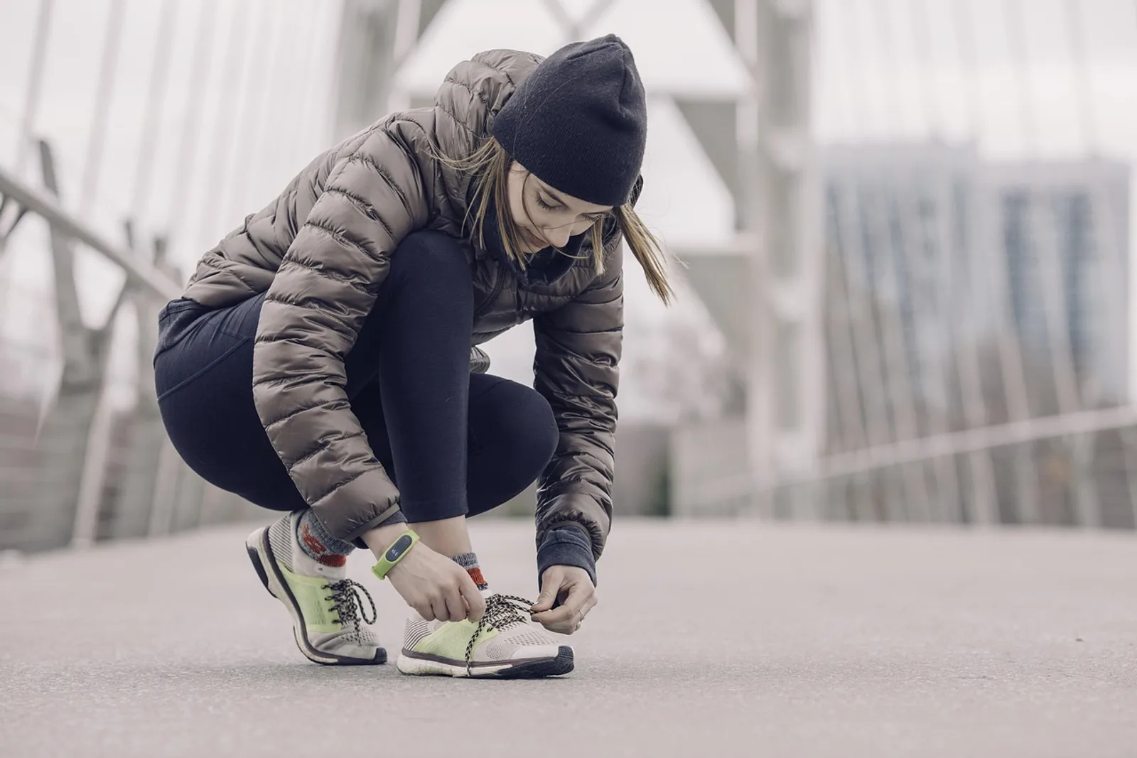 Woman tying her running shoes on a bridge: a small first step when you want to know how to build habits