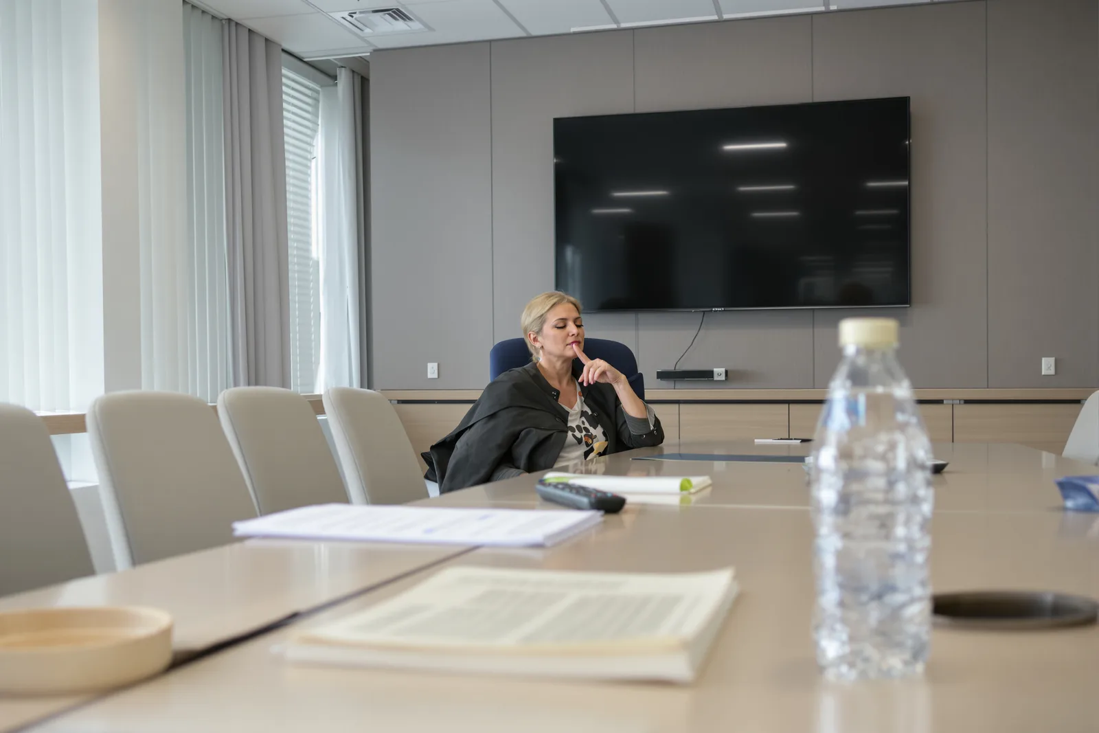 Female manager alone in an empty meeting room practicing her calm anchor before a board meeting, hypnosis for leadership step by step