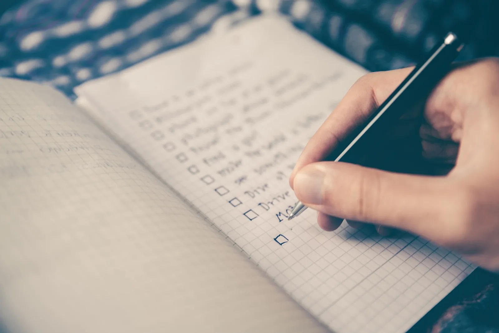 A hand adds another item to a long to-do list full of empty boxes: how to finish what you start instead of piling it up