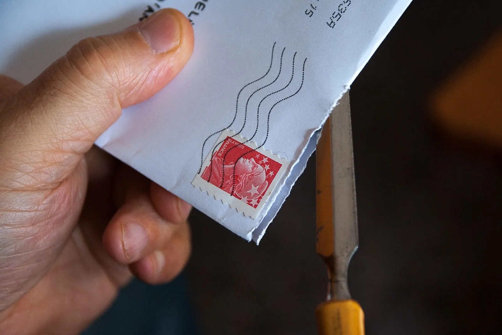 Hand opening an envelope with a letter opener: accepting what arrives instead of controlling everything, a way to stop being a perfectionist