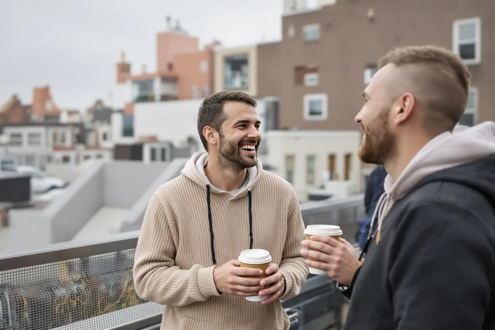 Zwei Kollegen lachen auf der Dachterrasse des Büros